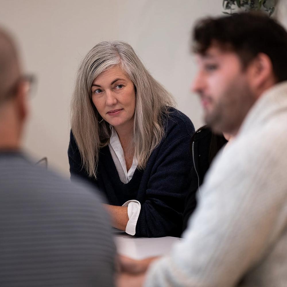 A middle-aged woman with a serious expression looks at a man as they are taking part in an invitational intervention hosted by Interventionist and Recovery Coach Michael Walsh