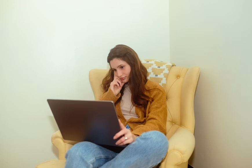 A woman seated with a laptop as she explores online counselling and therapy options.