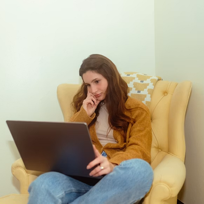 A woman seated with a laptop as she explores online counselling and therapy options.