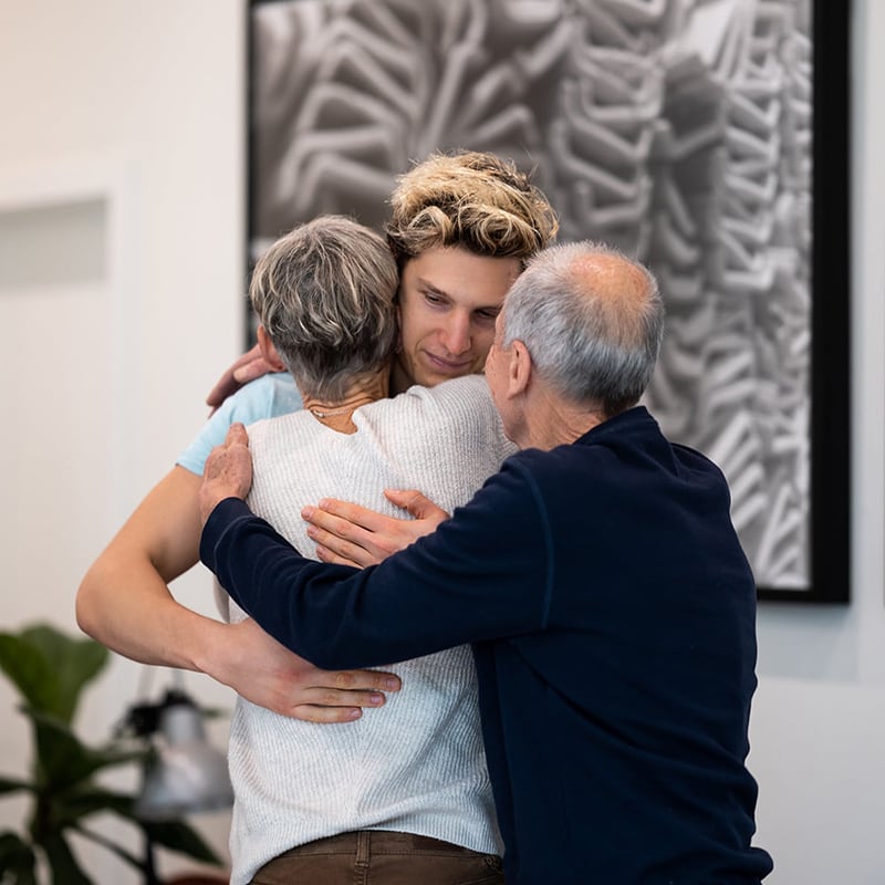 A man in his early 20s hugs his family after an invitational intervention hosted by Michael Walsh, professional Interventionist and Sober Coach