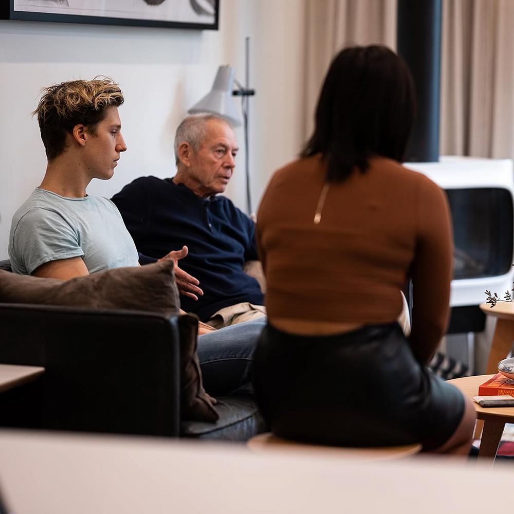 Three members of a family sitting in a living room and discussing drug and alcohol use during an invitational intervention organized and hosted by Michael Walsh and his team of Canadian Interventionists